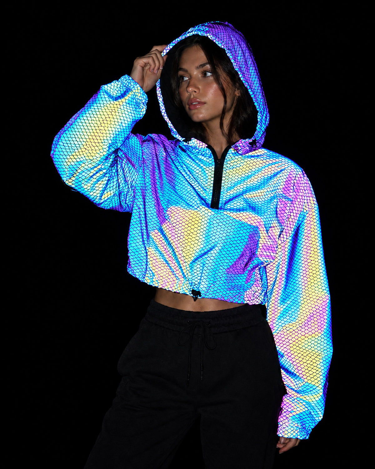 Scale reflective cropped hooded jacket showing a glowing fish-scale pattern under camera flash
