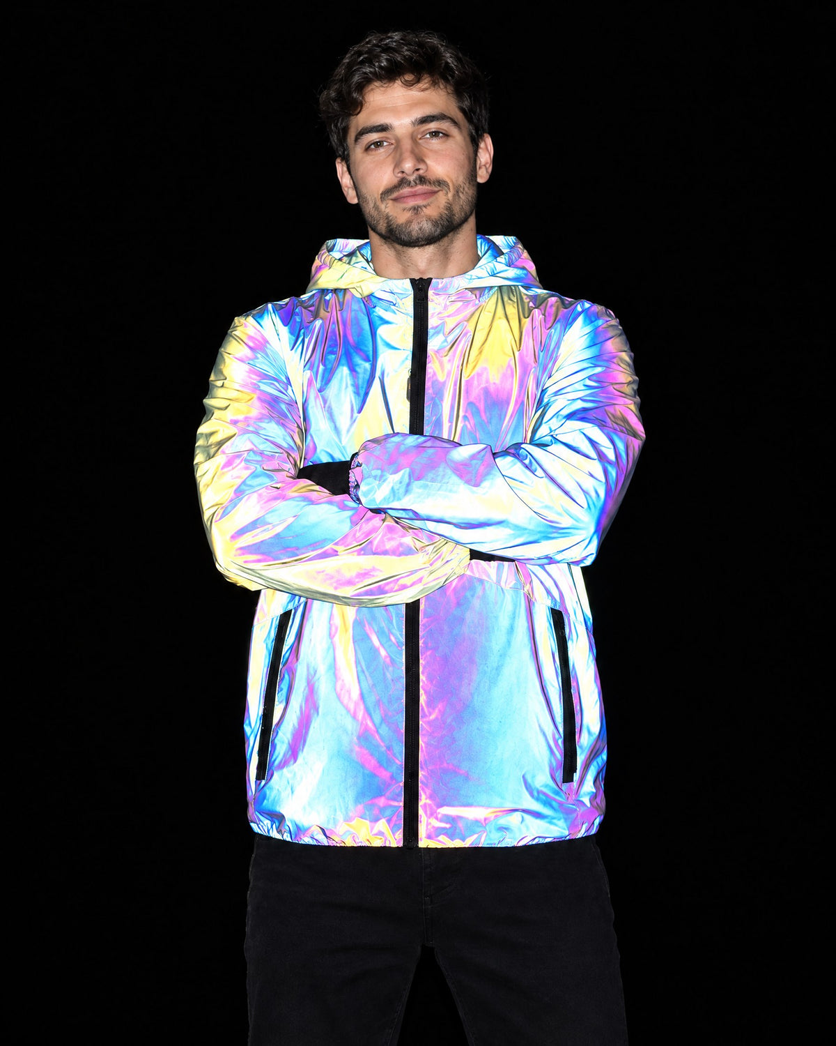 Man in a reflective full-zip hooded jacket with arms crossed, jacket lit by flash