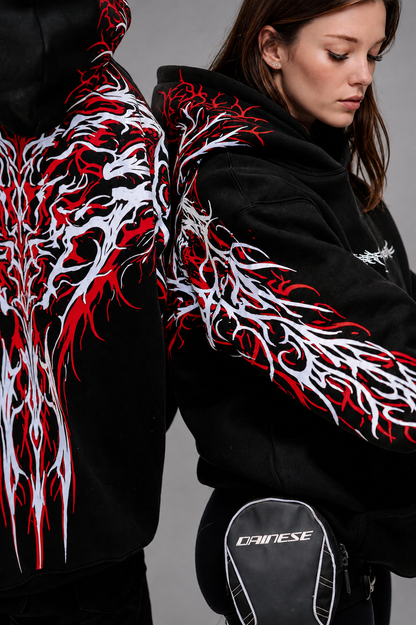 Two views of the Reflective Hoodie v2 side by side: the full red and white tribal back print, and a model in three-quarter view showing the sleeve print and the small white 444 mark on the chest.