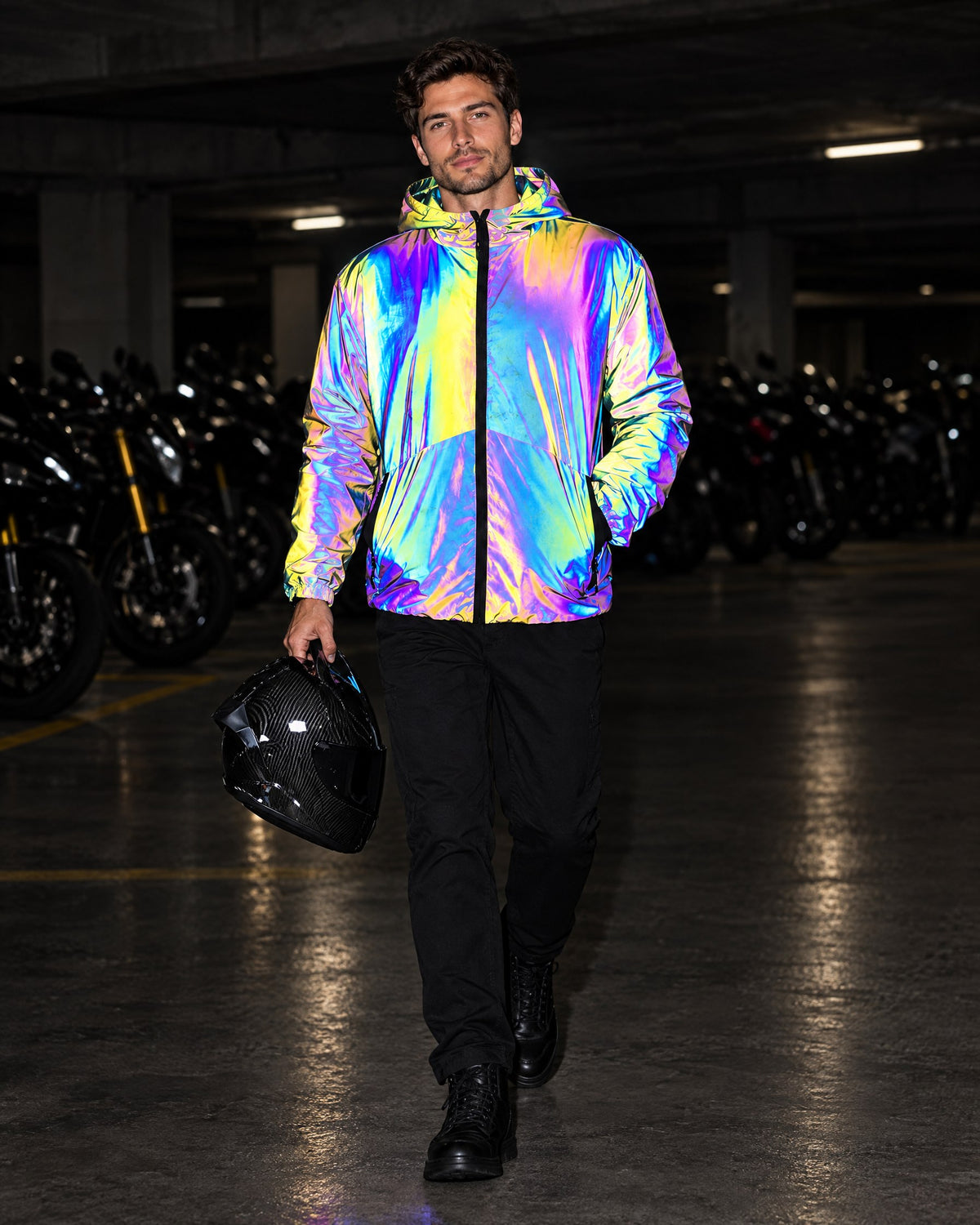 Man carrying a helmet through a parking garage, reflective jacket lit by flash