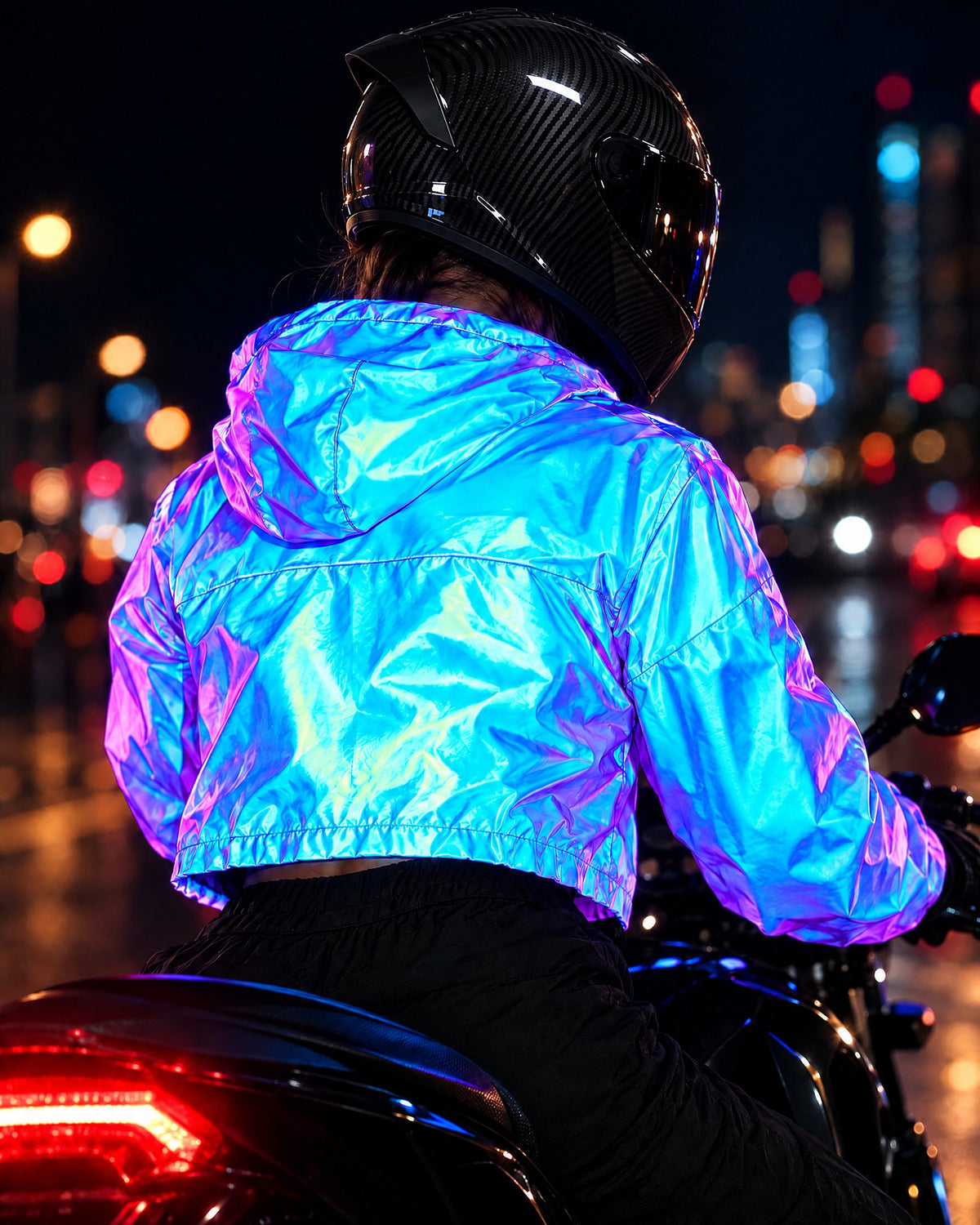 Back view of a rider in a carbon-look helmet and Cobalt reflective cropped jacket lit by headlights at night