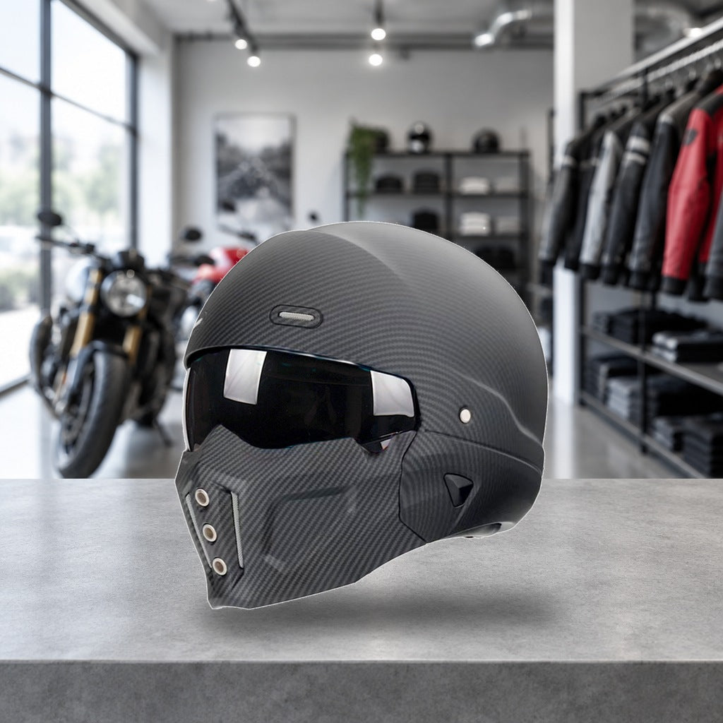 Switchback convertible motorcycle helmet in matte carbon-look weave, chin bar fitted, on a workshop bench