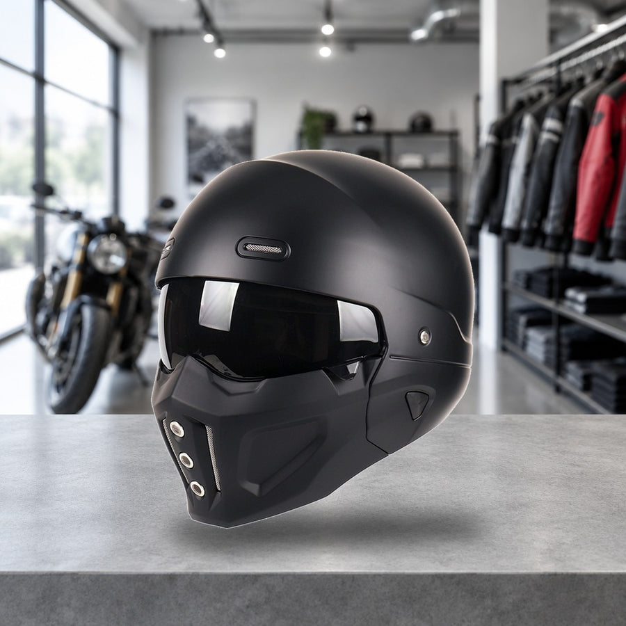 Switchback convertible motorcycle helmet in matte black, chin bar fitted and smoke shield down, on a workshop bench